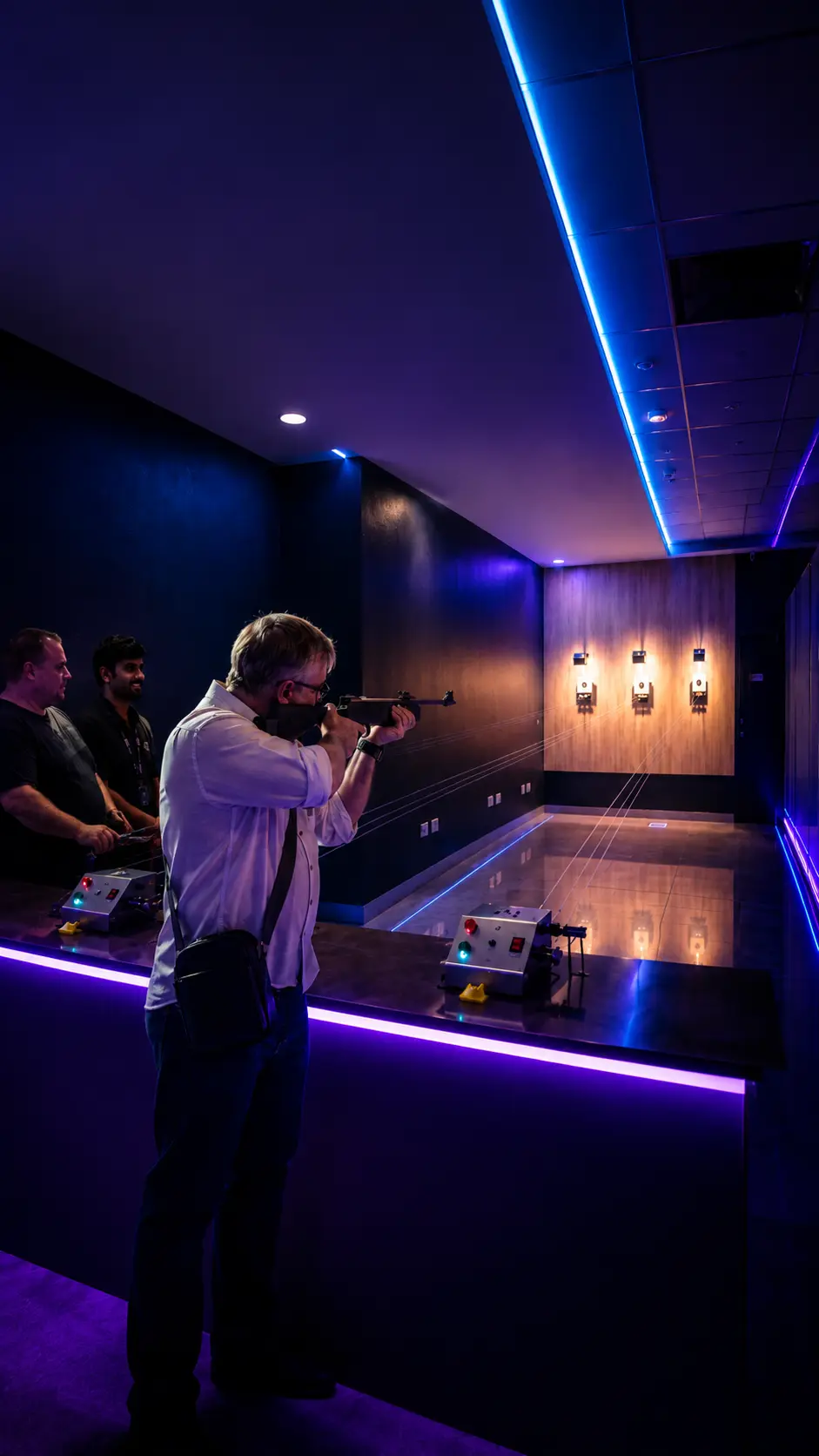 Player aiming air gun at targets in neon-lit indoor shooting range at Game Xtreme Hyderabad