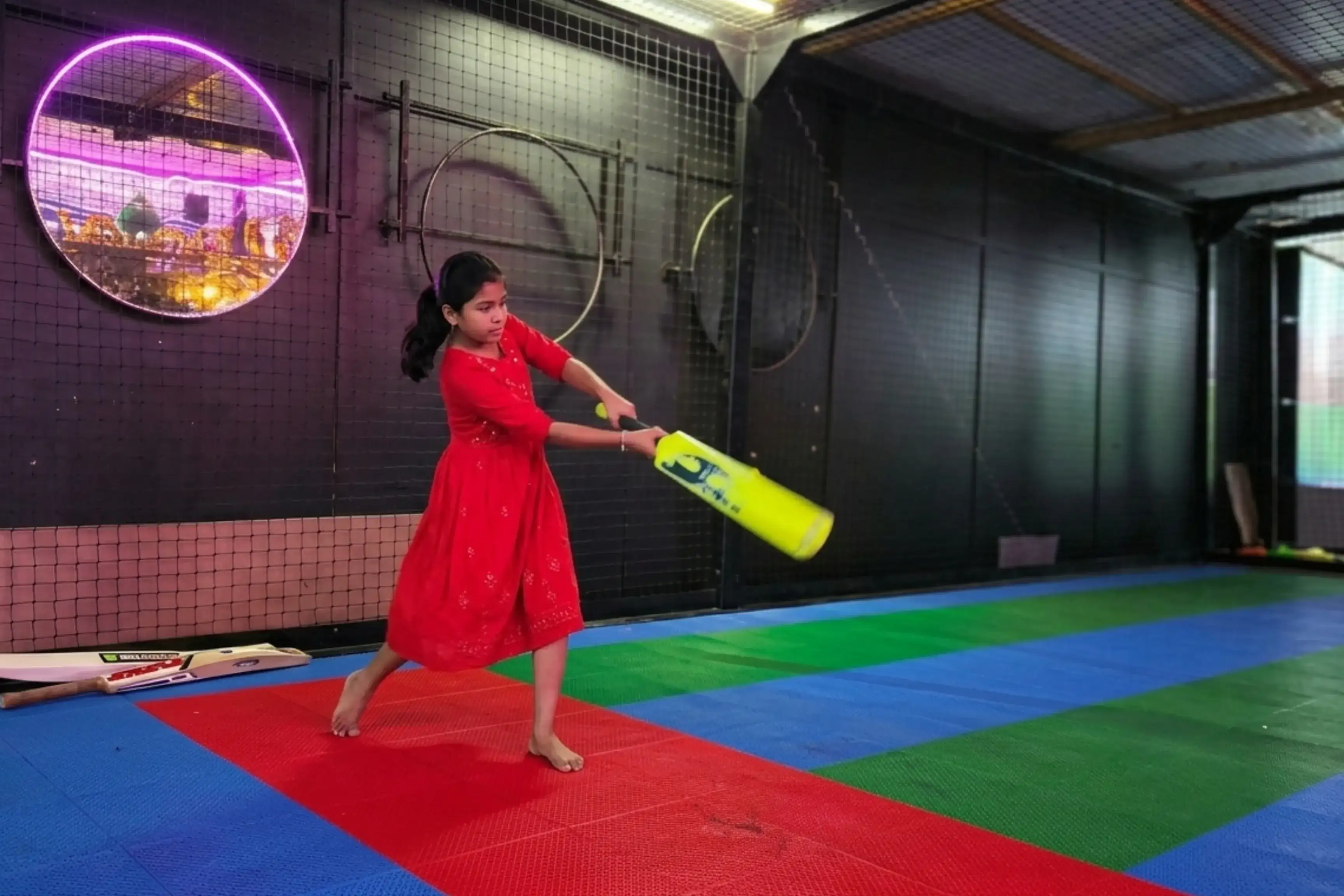 Young girl batting in cricket simulator at Game Xtreme — all ages welcome