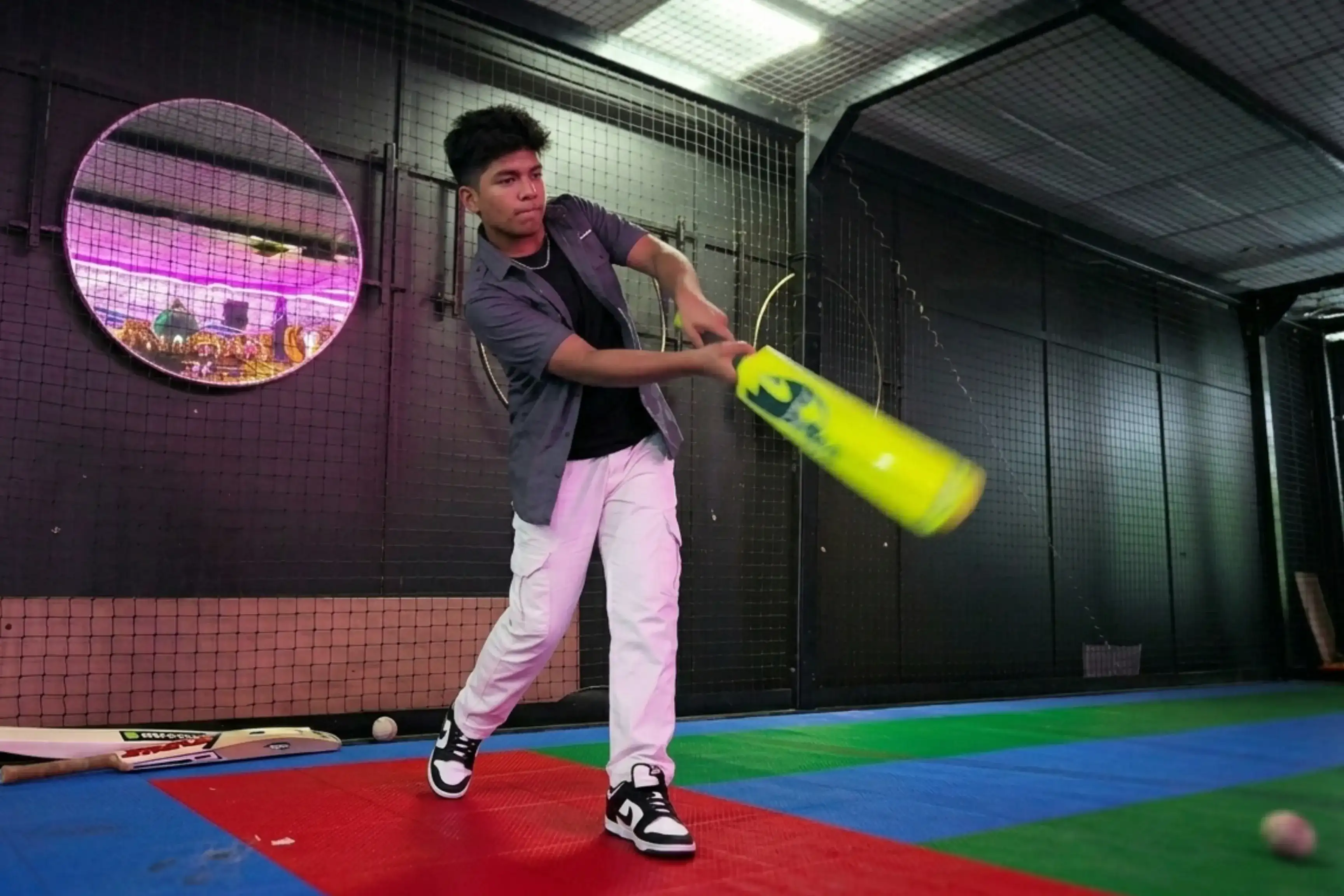 Teenager playing cricket simulator with full batting swing at Game Xtreme
