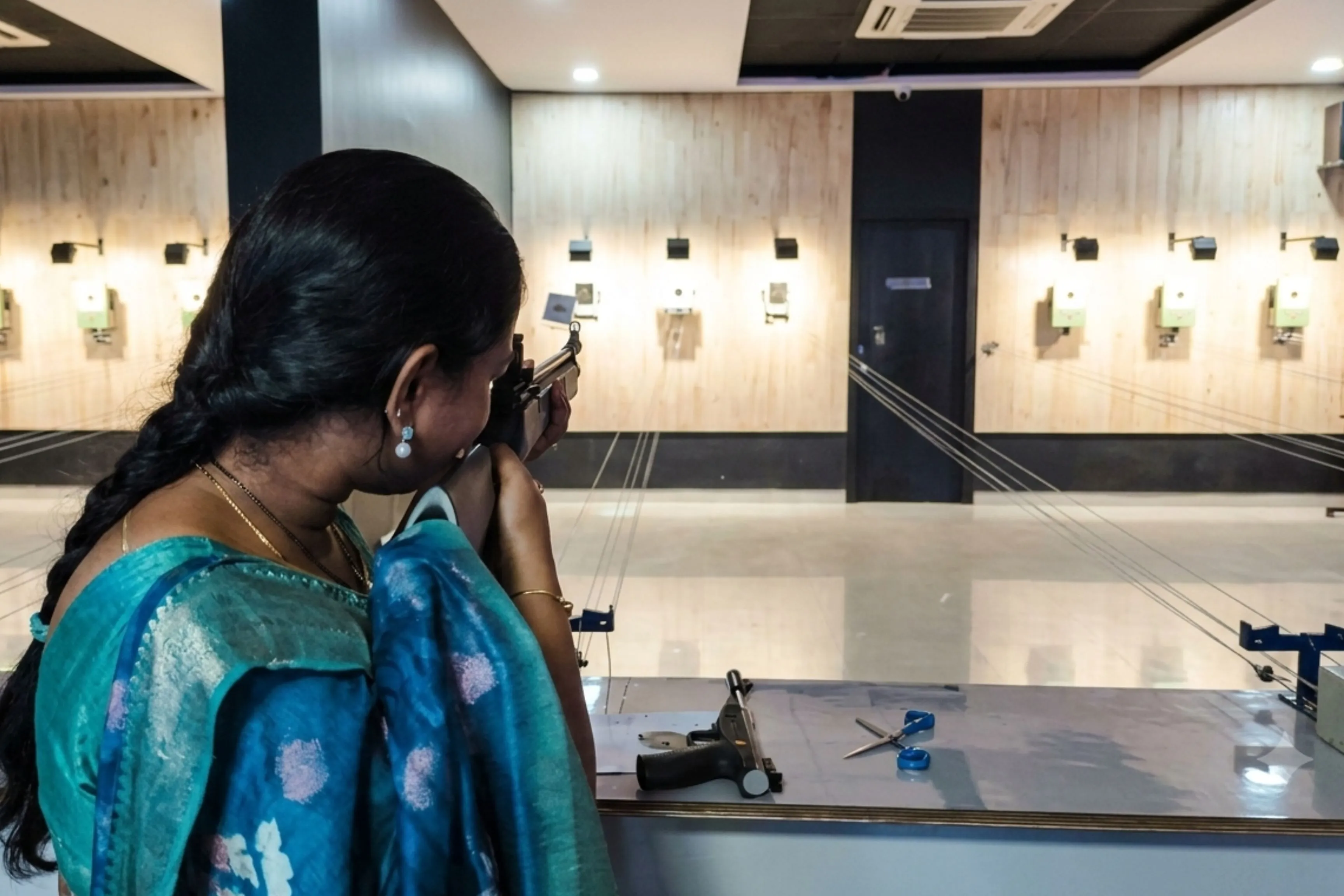 Woman aiming air gun at target in supervised indoor shooting range at Game Xtreme