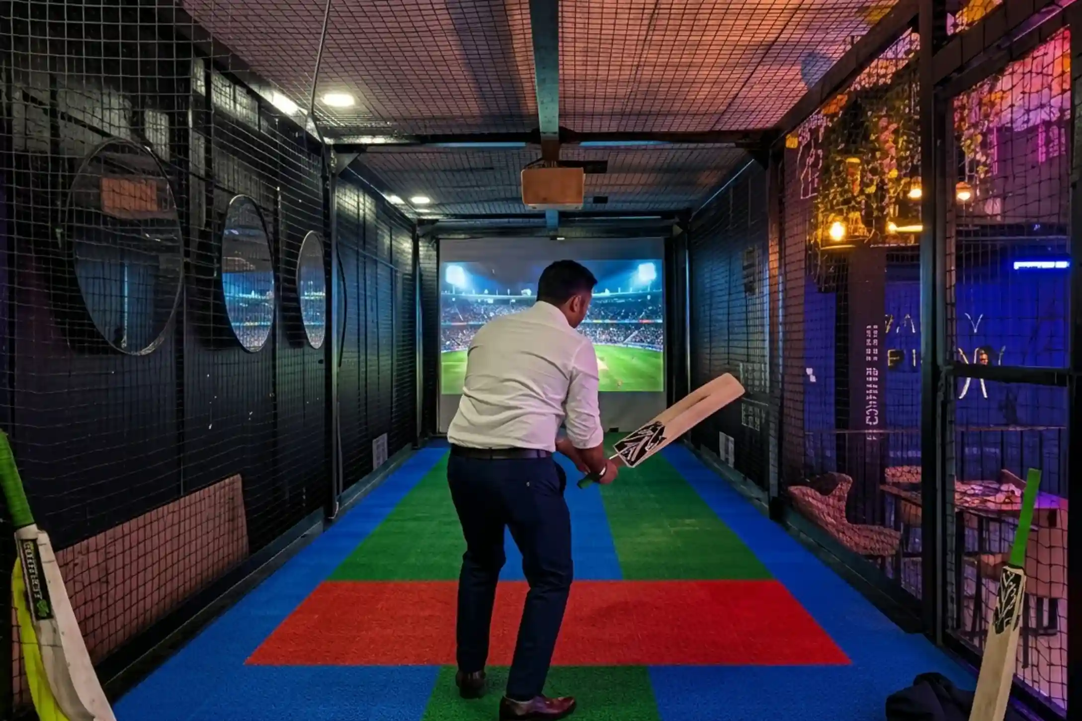 Player batting in cricket simulator while friends watch at Game Xtreme