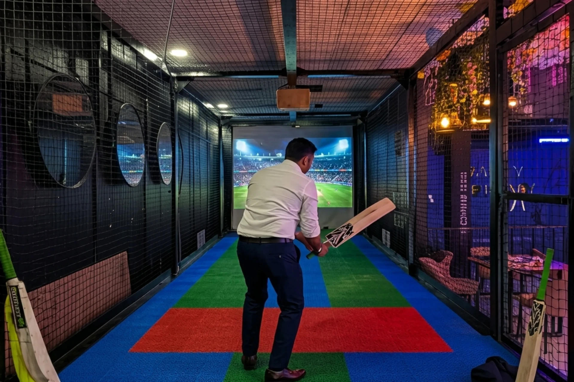 Player batting in cricket simulator facing projected stadium at Game Xtreme